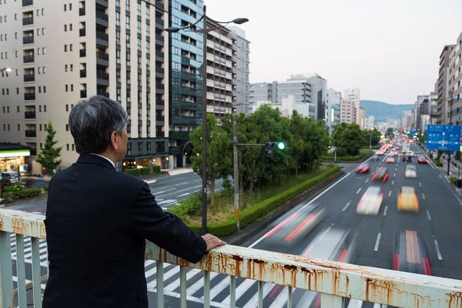 歩道橋から通りを見ている男性