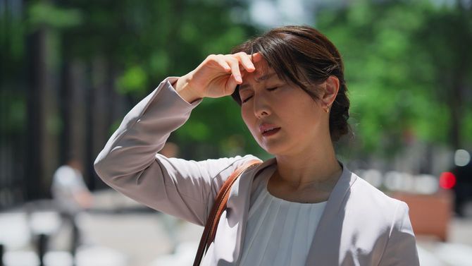 あまりの暑さに苦悶の表情を浮かべる女性