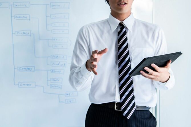 タブレットを手に説明をするビジネスマン