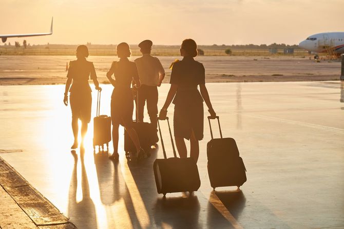 明るい夕日の中歩いている空港の乗組員