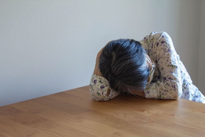 机に横たわるシニア女性