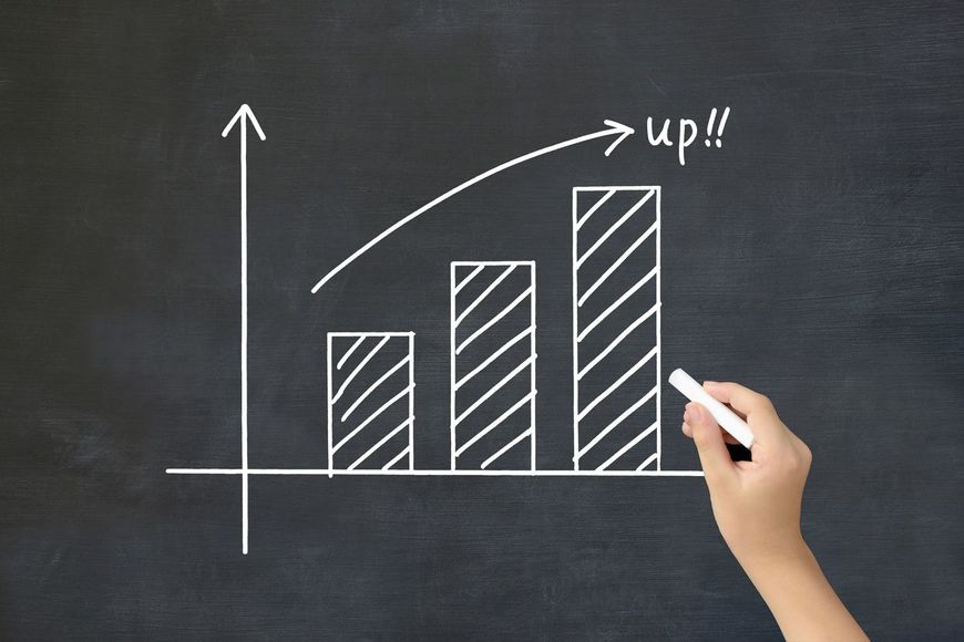 黒板に上向きの棒グラフを描く子供の手