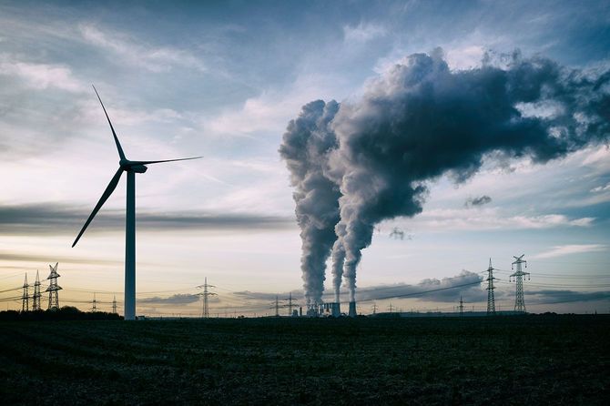 風力発電のタービンと、煙を上げる火力発電所
