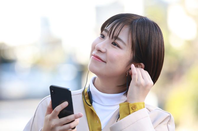 スマートフォンで音楽を聴いている女性