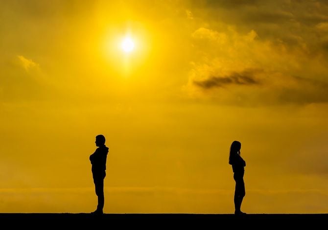 背を向けて離れた位置に立つ男女のシルエット