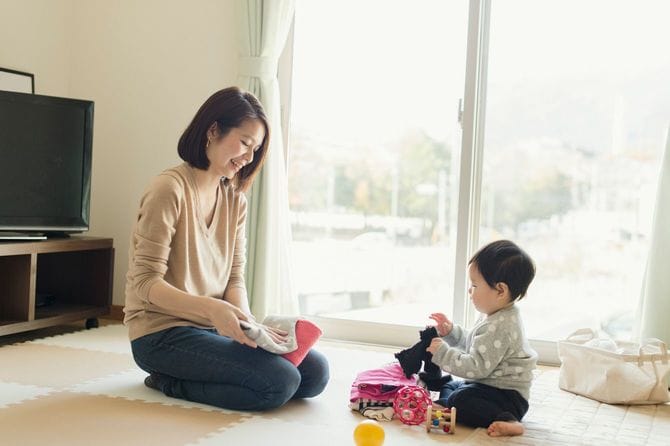 洗濯物を折りたたんで家事をしている母親