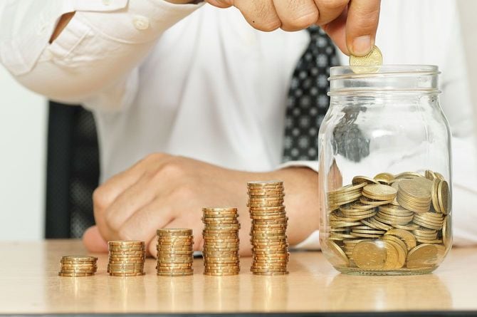 ビンにコインを貯めているビジネスマン