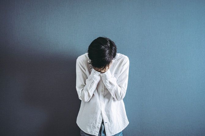 困りごとで顔を伏せる人のイメージ