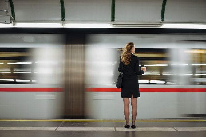 地下鉄のホームに立つスーツの女性