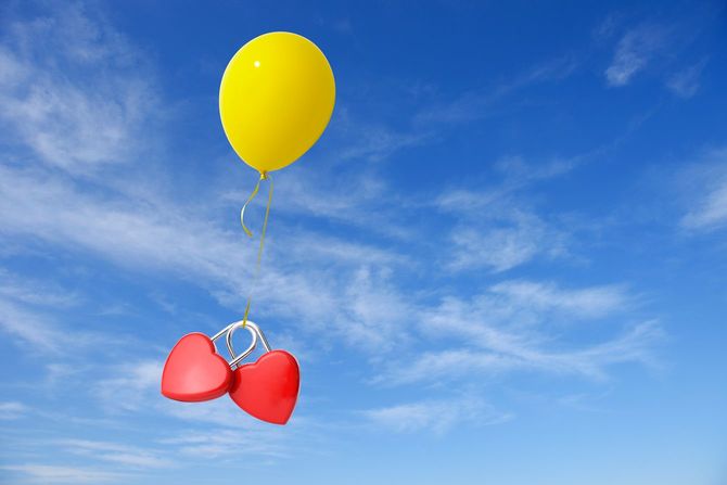 空中に浮かぶ黄色い風船と2つの赤いハート