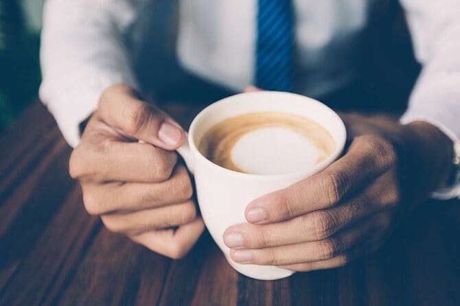 コーヒーカップを持つ男性の手