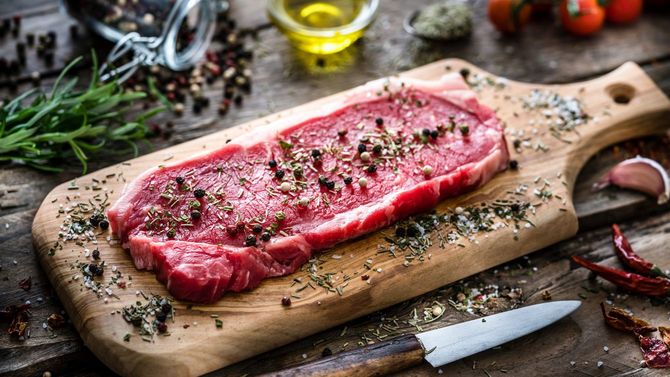 木製まな板の上に置かれたハーブやスパイスがかけられた生のフィレステーキ