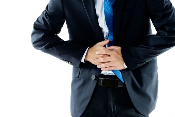 腹痛でおなかを押さえるビジネスパーソン