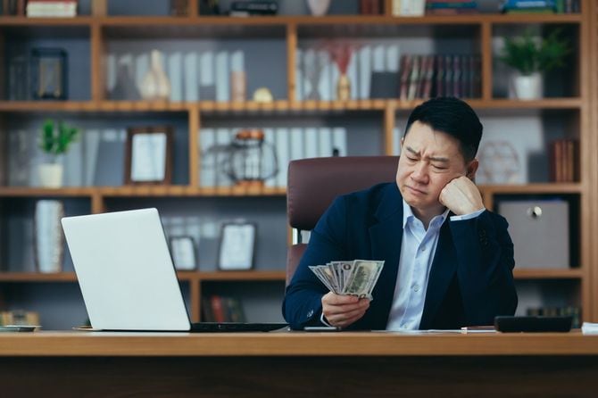 手に持った米ドル札を怪訝そうに見る男性