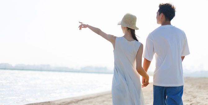 手をつないでビーチを歩くカップル