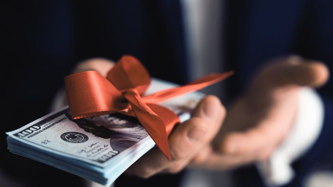 リボンがかけられた札束を差し出す男性の手元