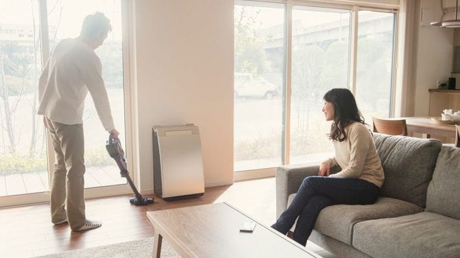 掃除機をかける夫とソファでリラックスする妻