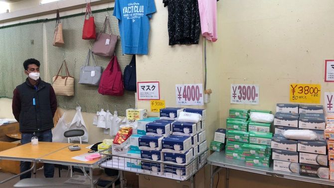 マスクの箱を机に積んで販売する、”カバン屋”のバングラデシュ人男性。