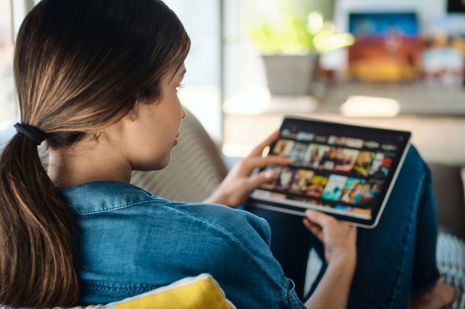 タブレットで観る映画を選ぶ女性