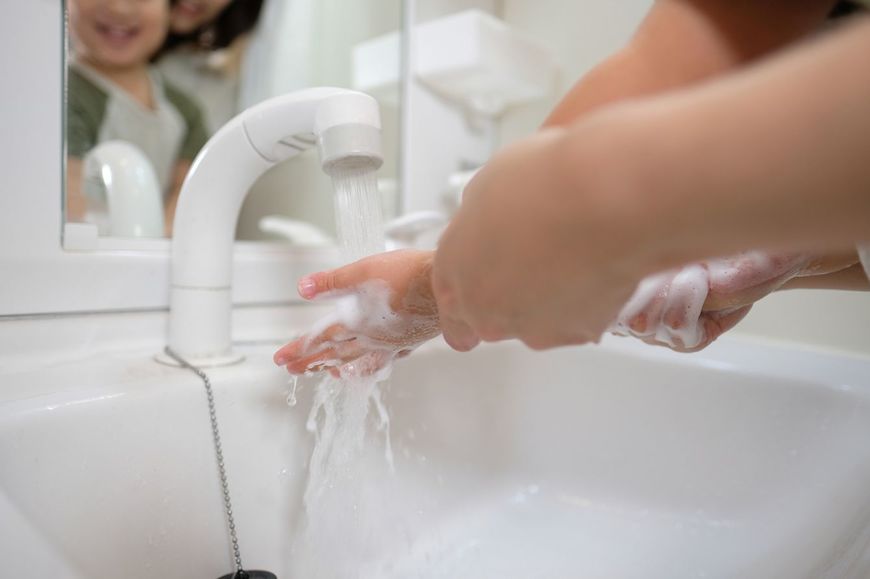 子どもの手洗いを手伝う母親
