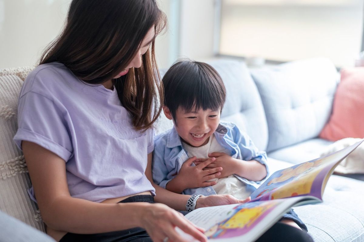 自宅で小さい息子と本を読むお母さん