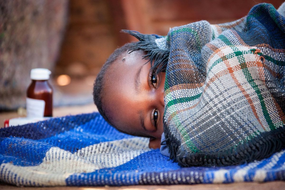 抗マラリア薬の横に寝ているアフリカの子供
