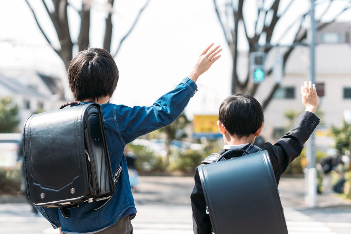 横断歩道を手を上げて渡る二人の小学生