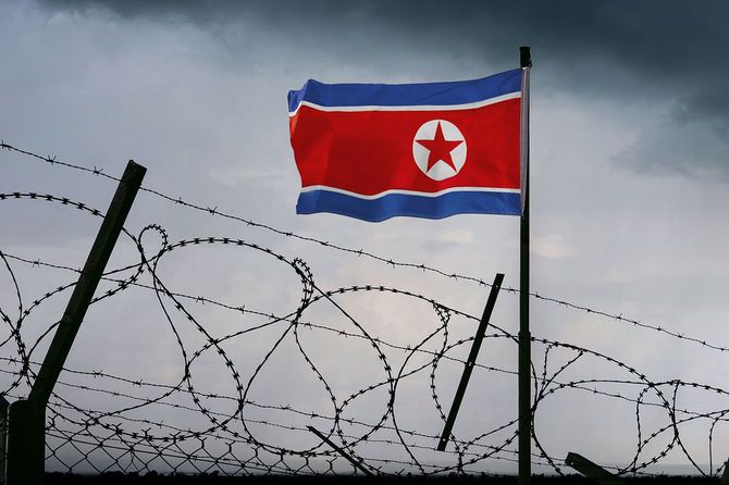 有刺鉄線越しにはためく北朝鮮の国旗