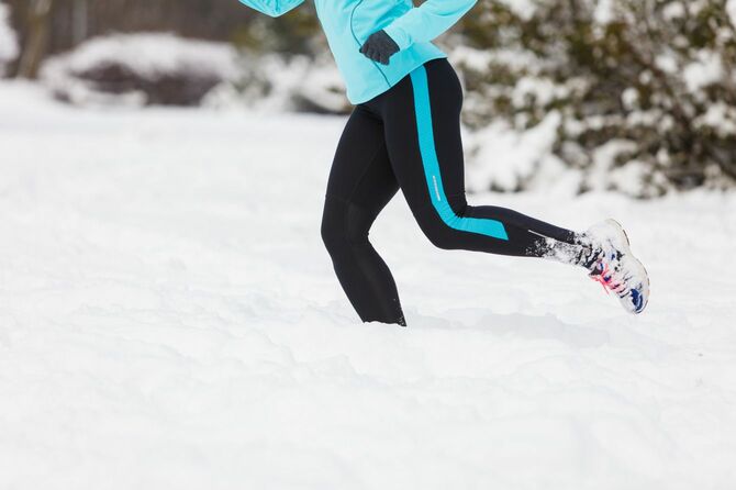雪の上を走るスポーツウェアの女性