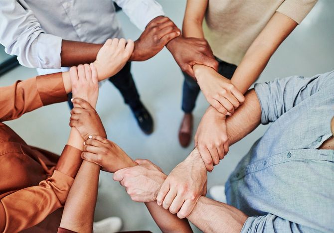 円状の形で互いの手首を握っているビジネスマンのグループ