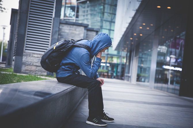 道路の脇に座り込む男性