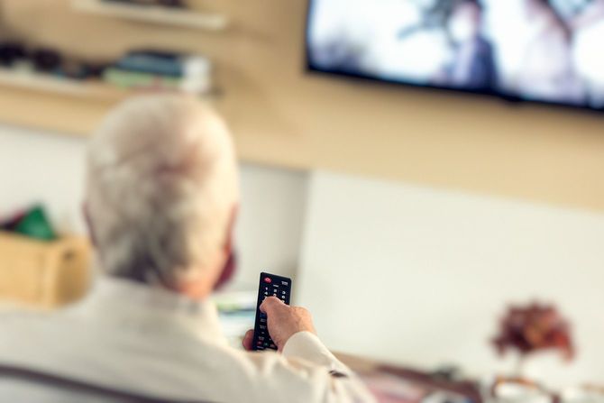 リモコンを持ちテレビを見ている高齢者