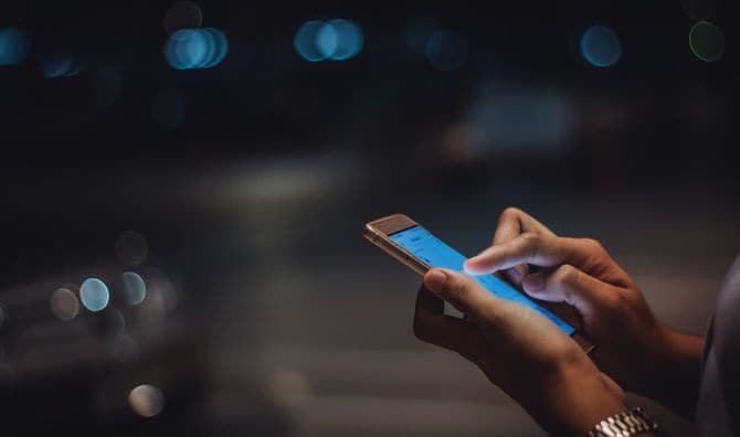 夜の街中でスマホを使用している人の手元