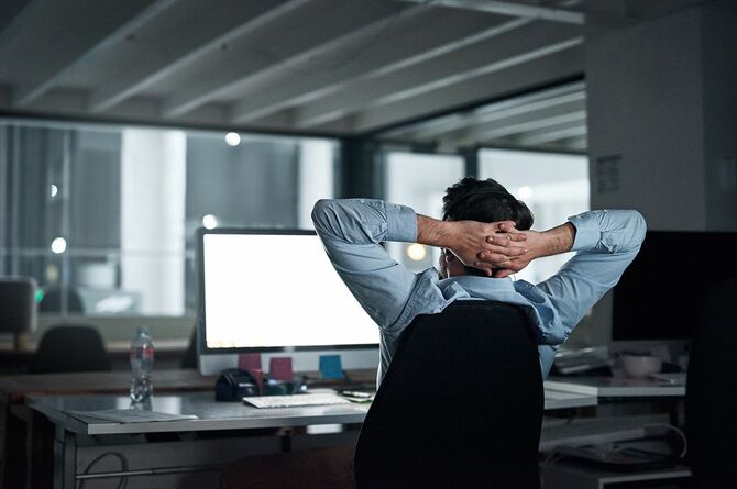 夜にオフィスで働いている間に休憩を取る若いビジネスマン