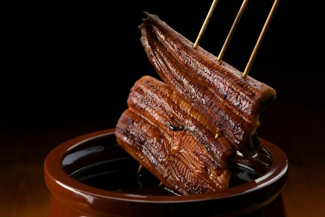 タレに浸される串焼きのうなぎ