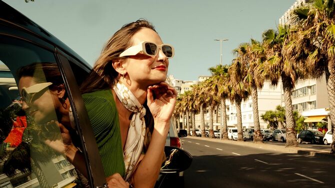 車の窓から身を乗り出す緑のドレスを着たファッショナブルな女性