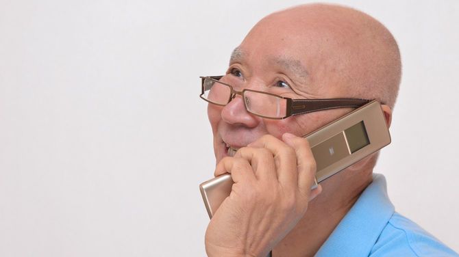 携帯電話で会話するシニア男性