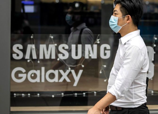 2020年7月14日、中国・上海のサムスンの店舗の前を通り過ぎる人。WHOは、ウイルスの起源をたどるため、疫学者と動物病の専門家の派遣