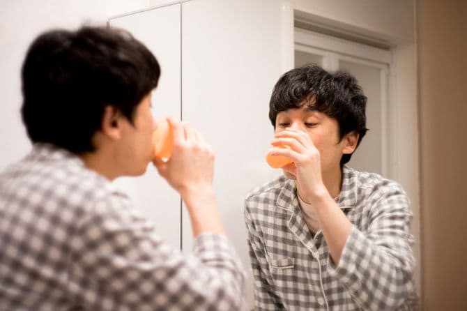 洗面所でうがいをするパジャマ姿の男性