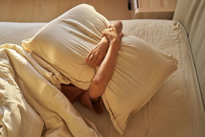 枕で頭を覆っている人