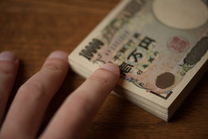 机の上に置かれた札束に指で触れている