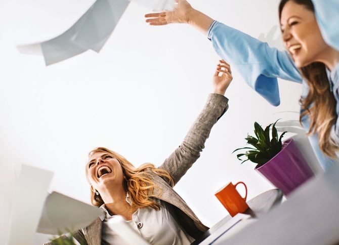 終業時間に書類を投げて笑顔のビジネスウーマンたち