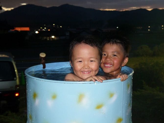 ドラム缶風呂に入る子どもたち