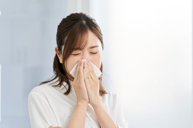 鼻炎で鼻をかむ女性