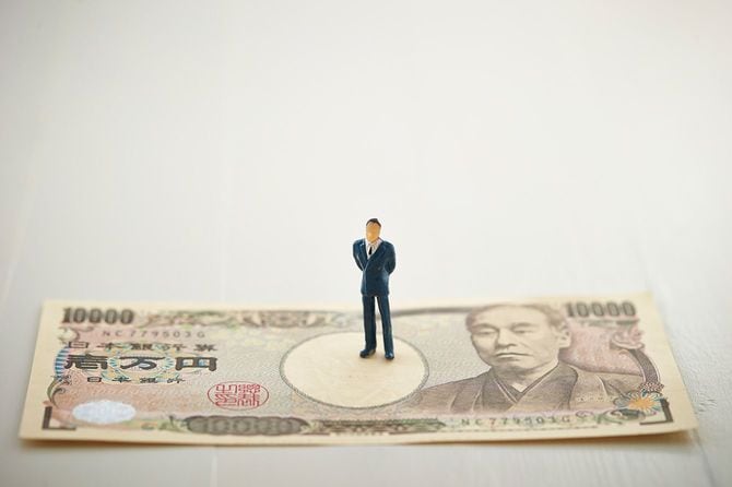 一万円紙幣の上に立つ男性の人形