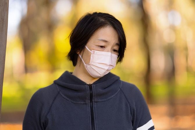 マスクをしてうつむく中年女性