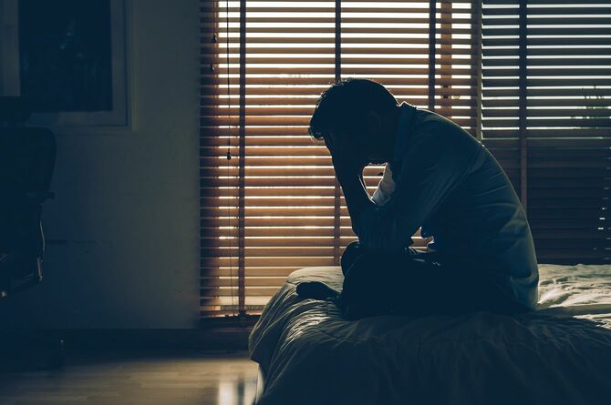 薄暗い部屋で頭を抱える人