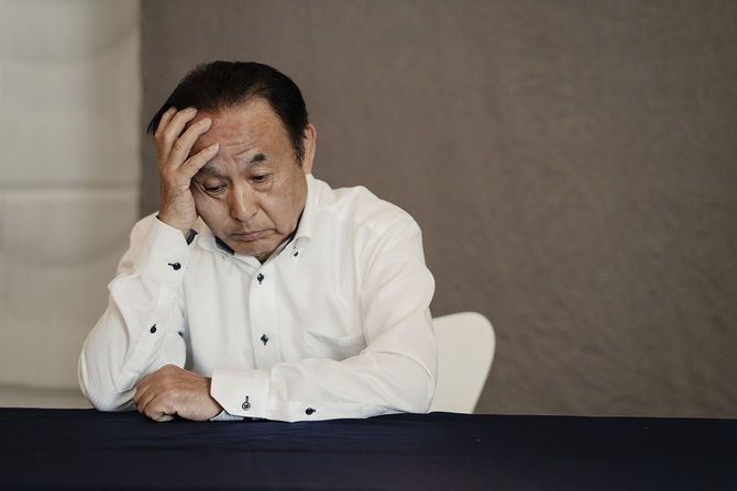 頭を押さえてうつむくシニア男性