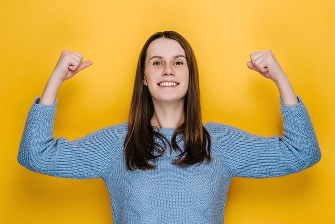 上腕二頭筋を示し、自信を持って見える魅力的な若い女性