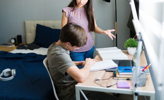 宿題をしている10代の息子を叱る母親